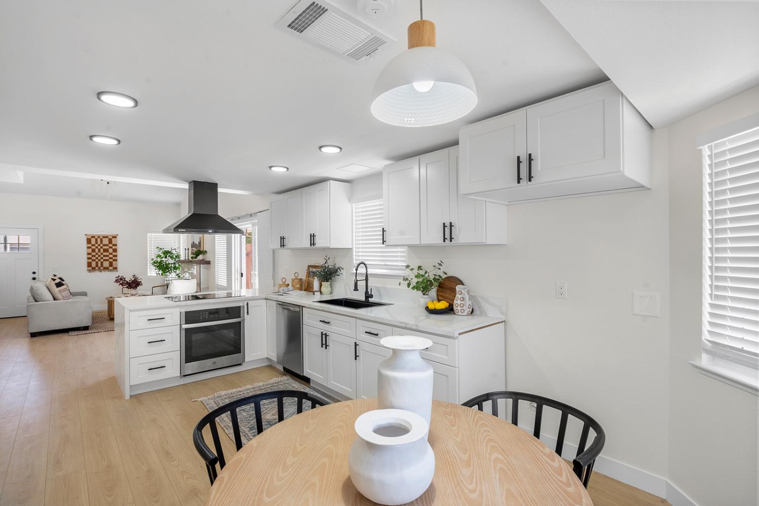 7531 Event Way Sacramento, CA 95842 - Photo 8 of 36 kitchen, appliances with stainless steel finishes, quartz countertops, peninsula exhaust hood, and white cabinetry