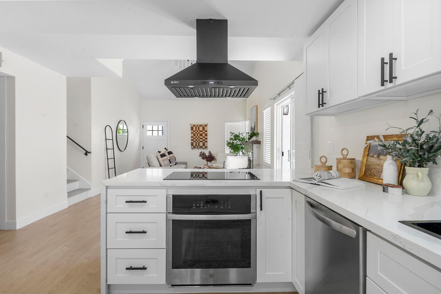 7531 Event Way Sacramento, CA 95842 - Photo 10 of 36 kitchen with a peninsula, stainless steel appliances, ceiling range hood, white cabinets, and light quartz countertops
