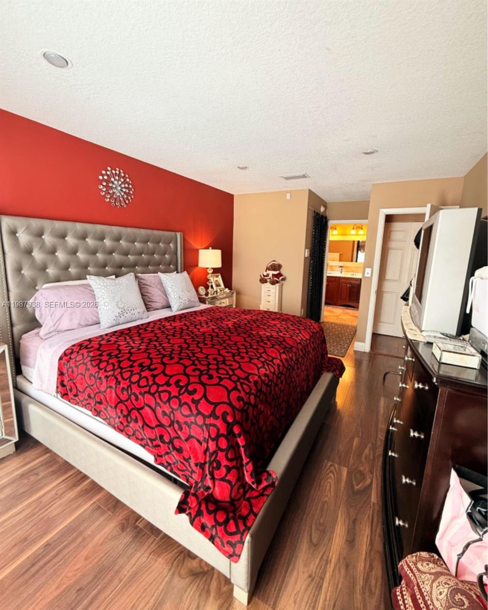 14856 Southwest 174th Street Miami, FL 33187 - Photo 12 of 28 a bed sitting in a bedroom next to a lamp with workspace