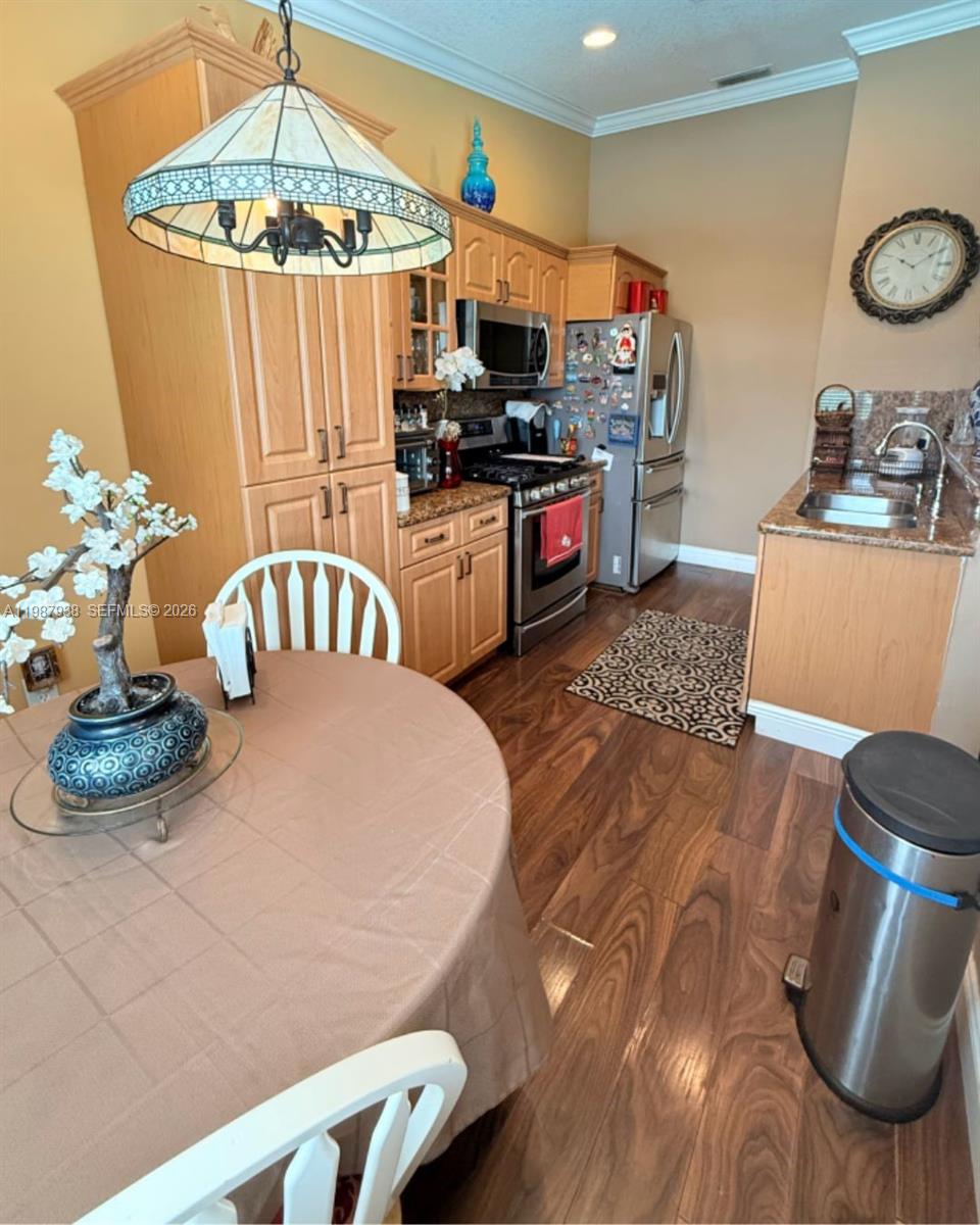 14856 Southwest 174th Street Miami, FL 33187 - Photo 23 of 28 a kitchen with stainless steel appliances a stove a chimney a dining table and chairs