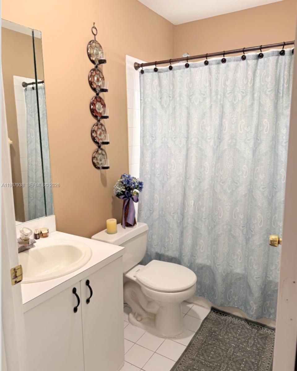14856 Southwest 174th Street Miami, FL 33187 - Photo 27 of 28 a bathroom with a sink a toilet a mirror and shower curtain