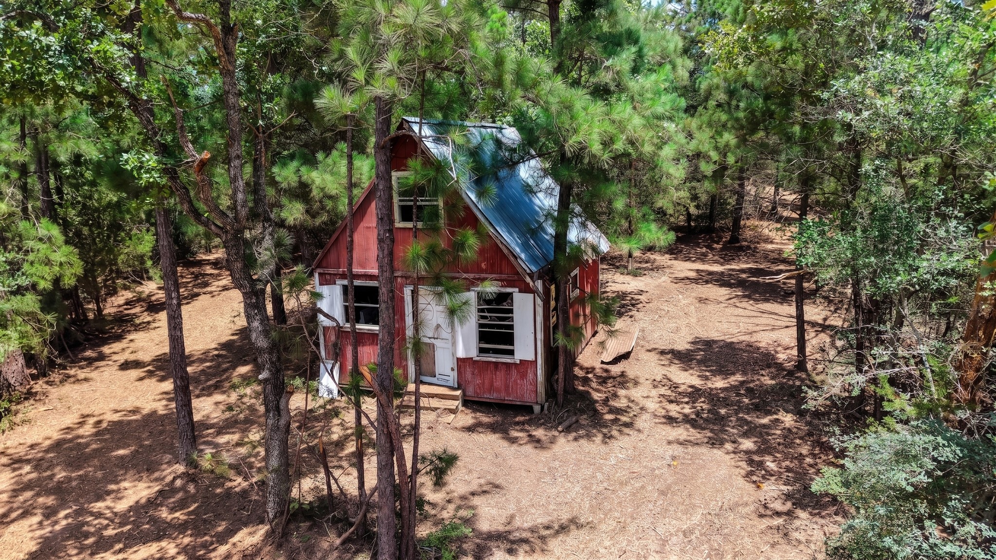 3428 (2.528 Acres In Lin Luce Ranches Milano, TX 76556 - Photo 5 of 23 A secluded red cabin nestled amongst dense pine trees, offering a rustic retreat in nature.