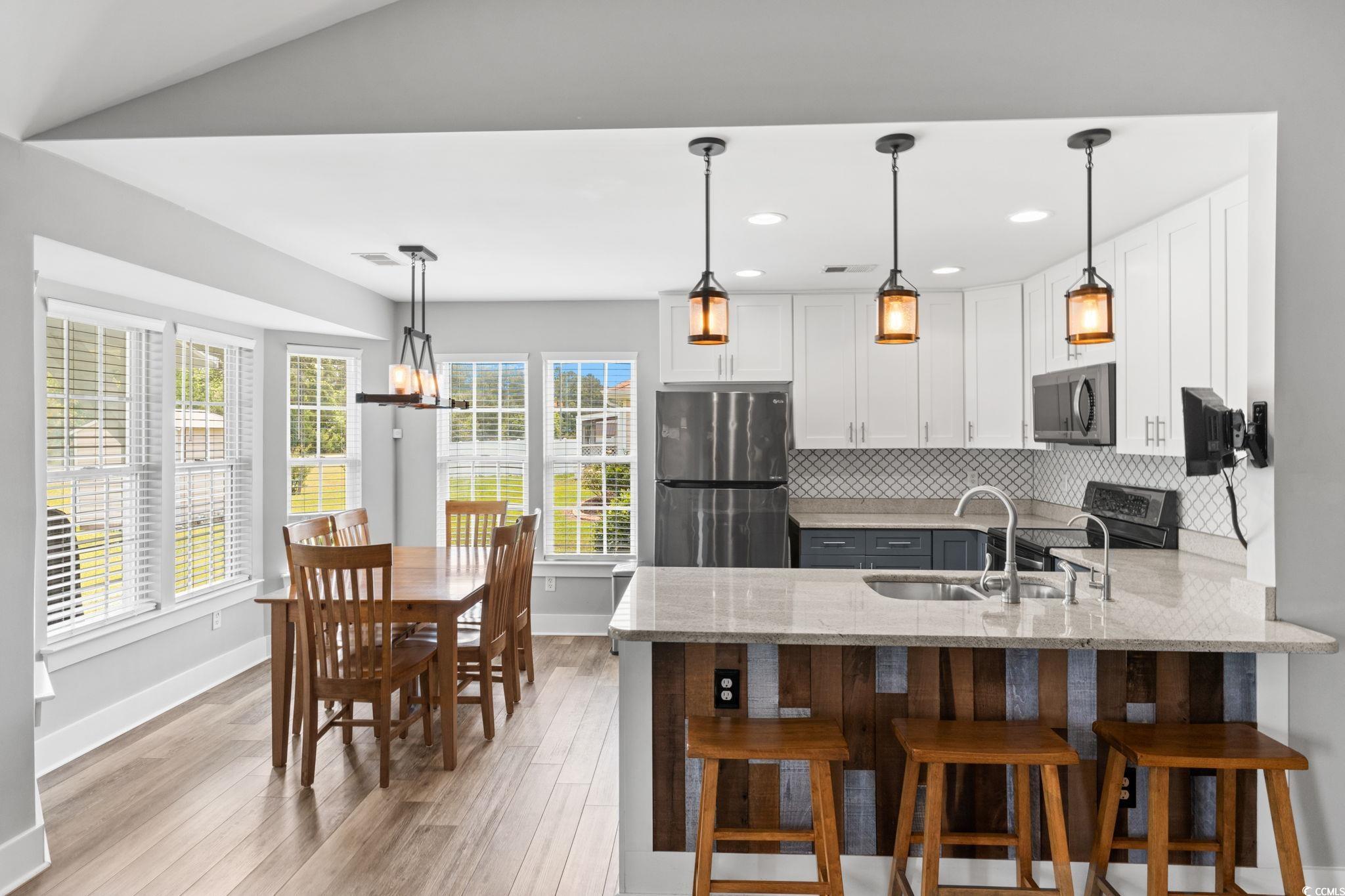 620 Seth Lane Longs, SC 29568 - Photo 9 of 35 Kitchen featuring appliances with stainless steel finishes, a sink, a peninsula, light stone countertops, and light wood finished floors