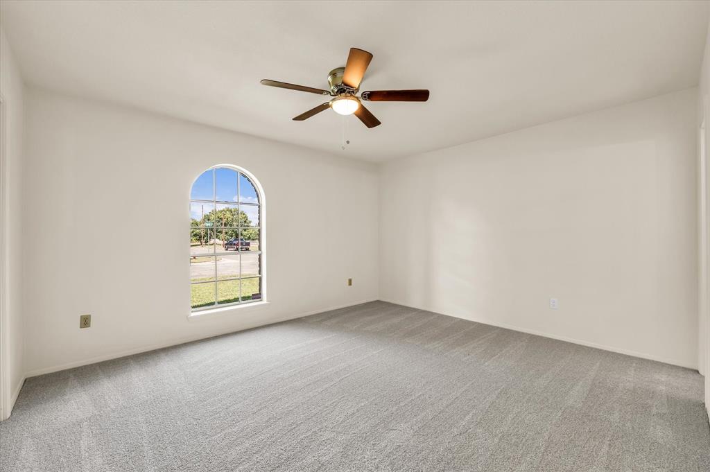141 Travis Lane Hewitt, TX 76643 - Photo 15 of 31 Spacious room featuring an arched window, light gray carpet, white walls, a ceiling fan with light fixture, and ample natural light