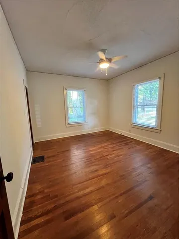 a view of an empty room with wooden floor and a window