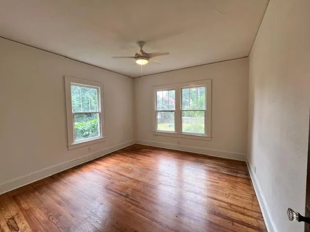 a view of an empty room with wooden floor and a window