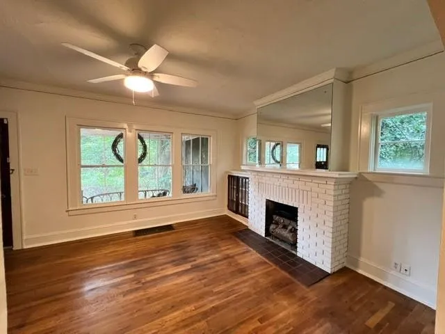 an empty room with windows fireplace and wooden floor