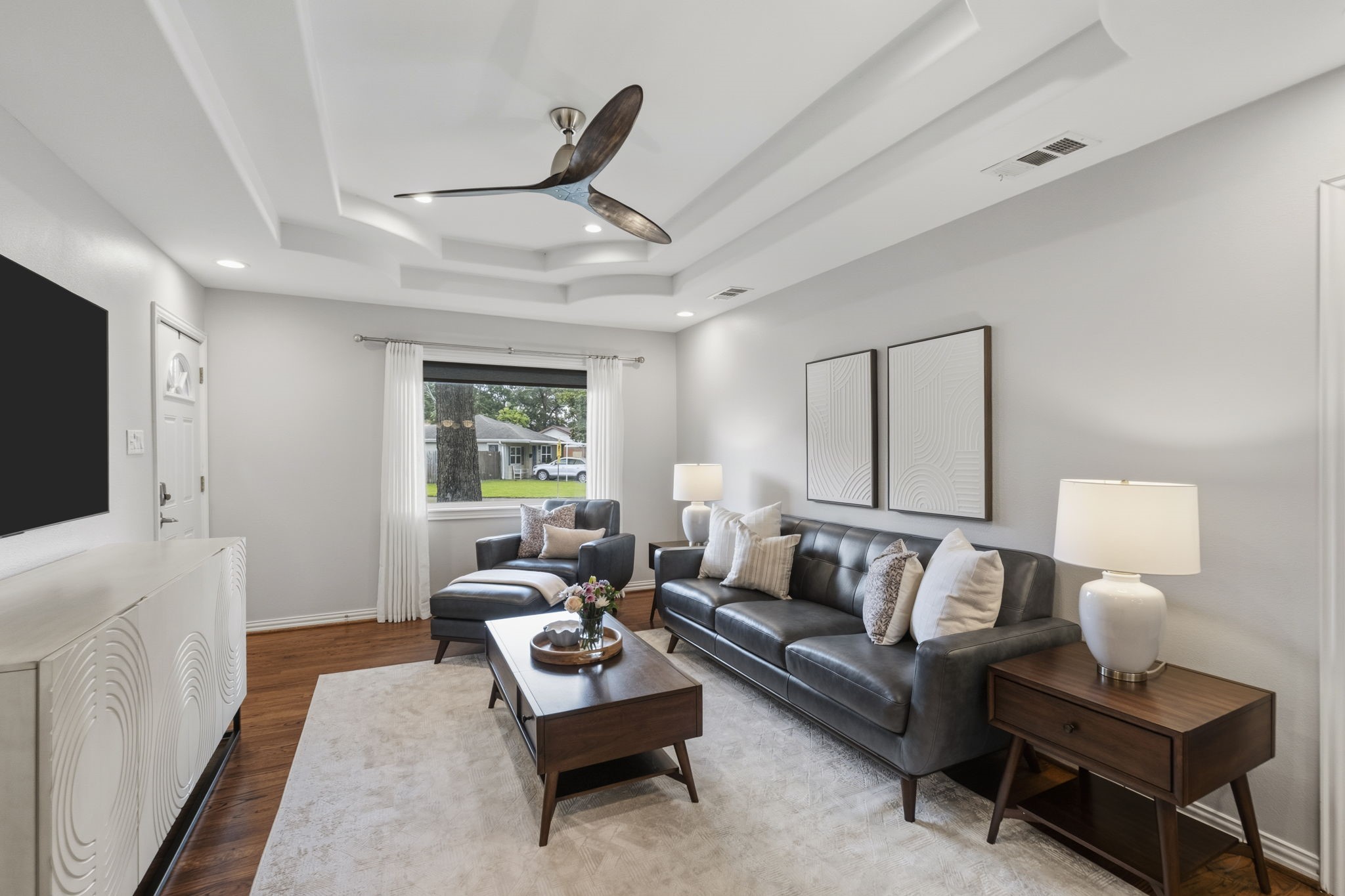 4733 Carleen Road Houston, TX 77092 - Photo 4 of 22 Natural light pours into the living room, where tray ceilings, hardwood floors, and recessed lighting create a warm, inviting gathering space.
