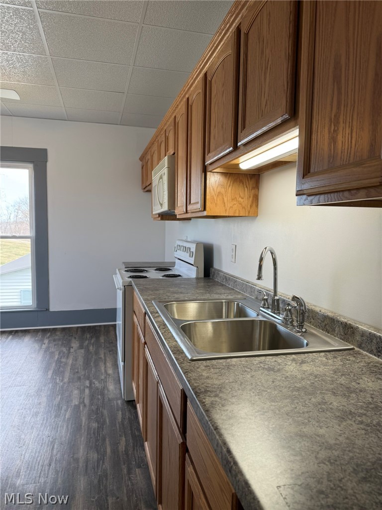 23033 Cadiz Road Freeport, OH 43973 - Photo 26 of 31 Kitchen featuring white appliances, dark wood-style floors, wood finish cabinetry, dark countertops, and a drop ceiling