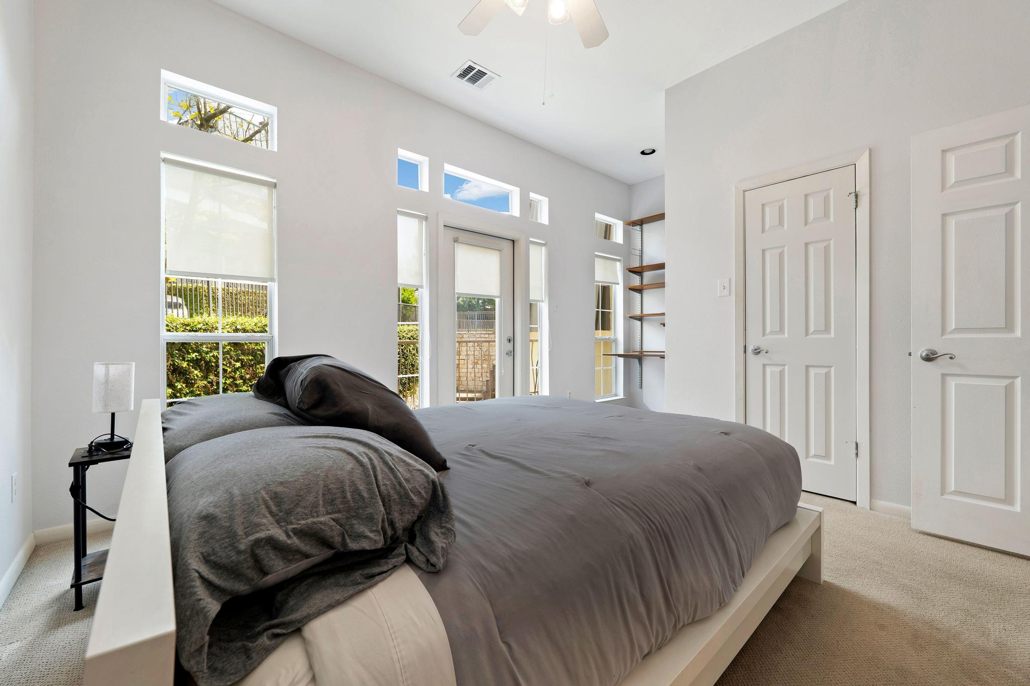 2918 Ranch Road 620, Unit J162 Austin, TX 78734 - Photo 23 of 26 Bedroom featuring high ceilings, multiple windows with roller shades, a ceiling fan, built-in shelving, and carpet flooring