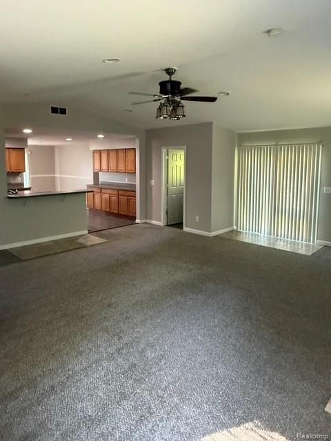 465 Trombley Road Troy, MI 48083 - Photo 2 of 24 Carpeted living area featuring a ceiling fan with integrated lighting, sliding glass door with vertical blinds, and a kitchen pass-through with a built-in counter