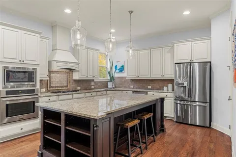 a kitchen with stainless steel appliances granite countertop a stove a sink dishwasher a oven a dining table and chairs with wooden floor