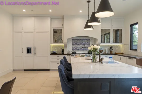 a kitchen with stainless steel appliances granite countertop a sink a stove a refrigerator a dining table and chairs