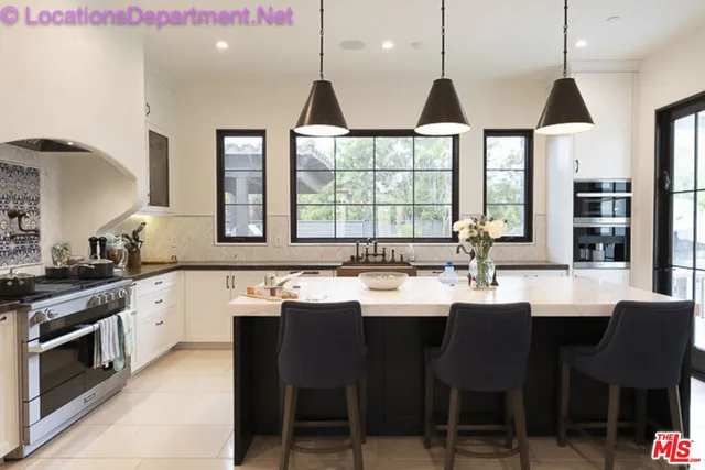 a kitchen with stainless steel appliances granite countertop a sink a stove and chairs