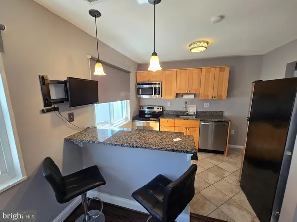 a kitchen with stainless steel appliances granite countertop a sink dishwasher a refrigerator a microwave oven with granite countertops and cabinets