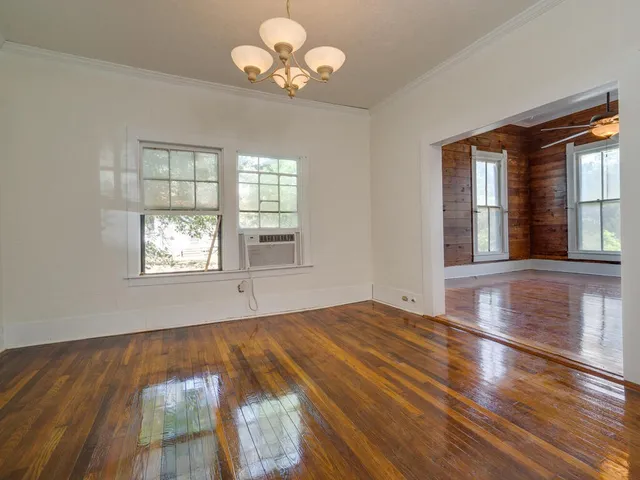 a view of an empty room with wooden floor and a window