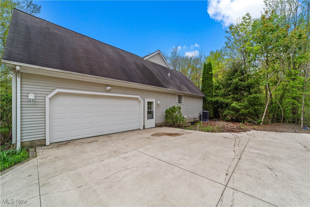 9540 South Brown Road Chardon, OH 44024 - Photo 18 of 19 View of home's exterior featuring concrete driveway, a shingled roof, central AC unit, and a garage