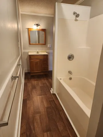 a bathroom with a tub a sink and wooden floor