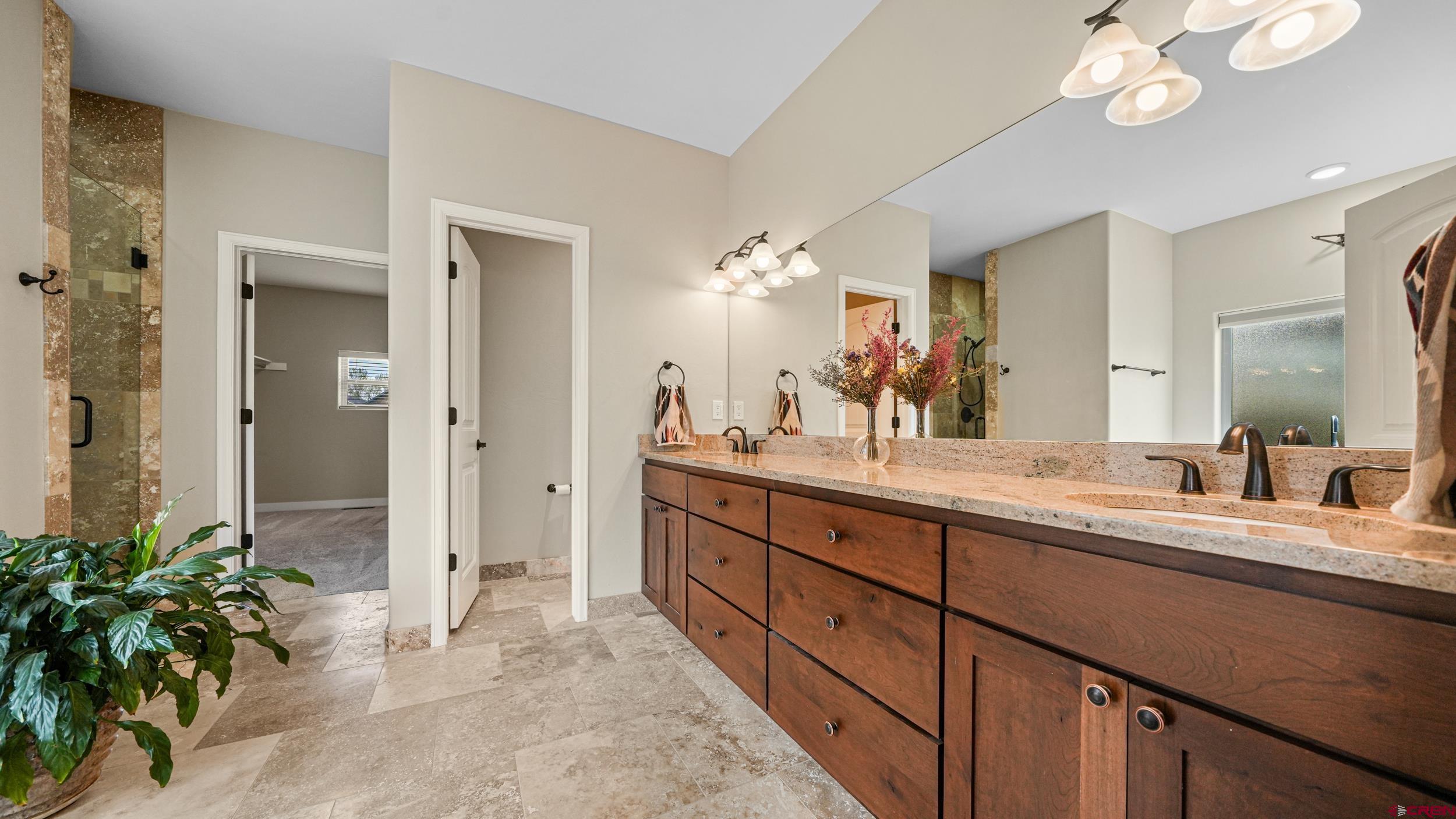 2042 Constitution Loop Montrose, CO 81401 - Photo 16 of 42 a spacious bathroom with a granite countertop sink a mirror and a shower
