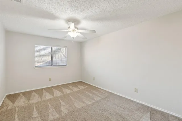 an empty room with windows and ceiling fan