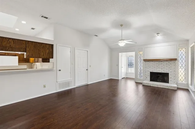 a view of empty room with wooden floor and fireplace