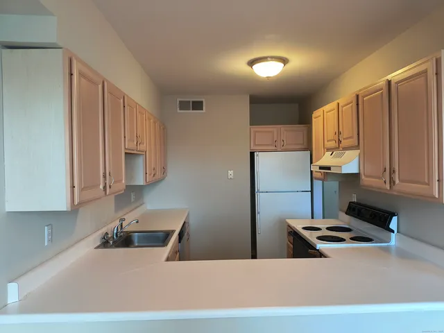 a kitchen with stainless steel appliances granite countertop a refrigerator a stove and a sink