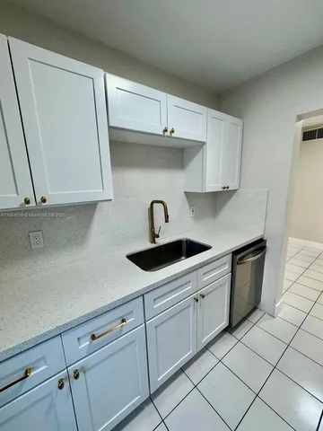 a kitchen with white cabinets a sink and dishwasher