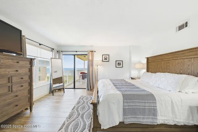 a bedroom with a bed and a flat tv screen on dresser