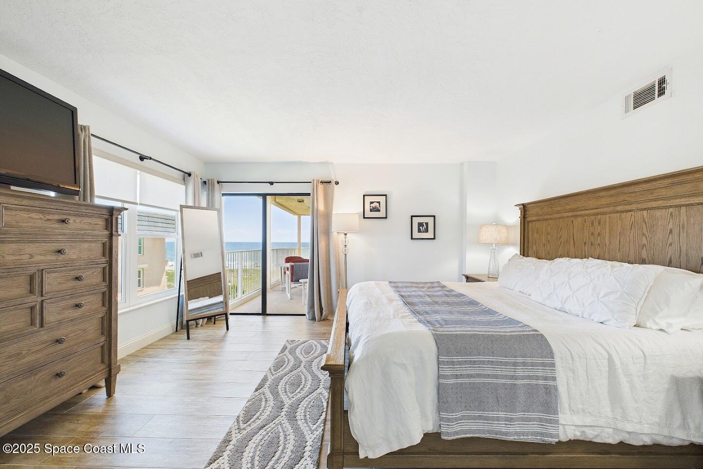 55 North 4th Street, Unit 401 Cocoa Beach, FL 32931 - Photo 23 of 34 a bedroom with a bed and a flat tv screen on dresser