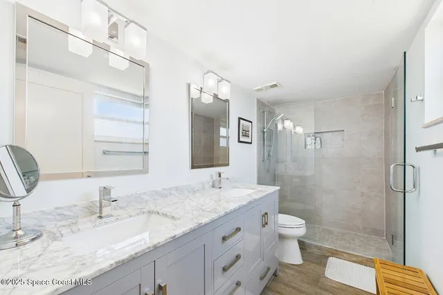 a bathroom with a granite countertop sink a toilet and shower