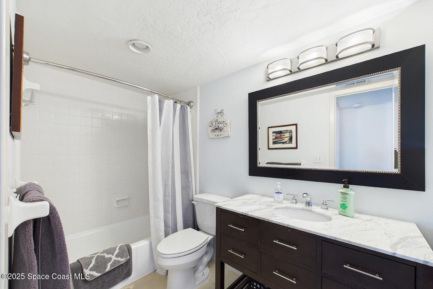 55 North 4th Street, Unit 401 Cocoa Beach, FL 32931 - Photo 28 of 34 a bathroom with a toilet a sink a mirror a vanity and shower