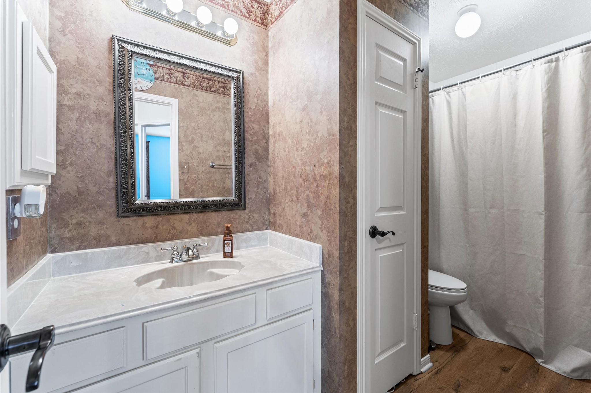 17618 Mill Springs Drive Spring, TX 77379 - Photo 19 of 26 This bathroom features a stylish vanity with a porcelain countertop, framed mirror, and modern lighting. The space includes a shower with a curtain and a toilet, all complemented by tile tyle flooring and neutral wall tones.
