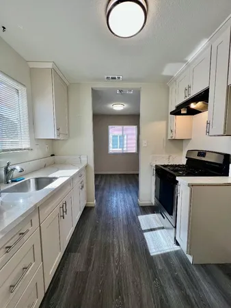 a kitchen with granite countertop a sink cabinets and wooden floor
