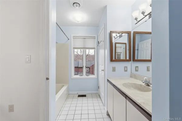 a bathroom with a tub sink and mirror
