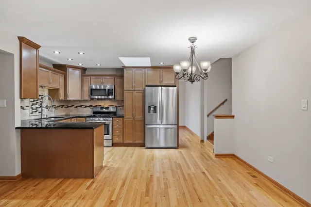 a kitchen with stainless steel appliances a refrigerator and a chandelier