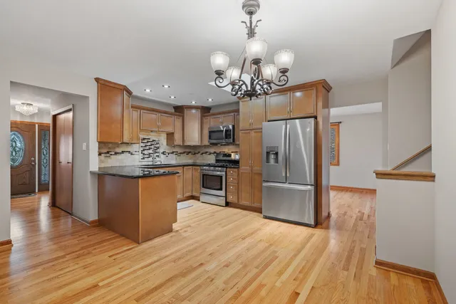 a kitchen with stainless steel appliances granite countertop a refrigerator a oven a stove and a wooden floors