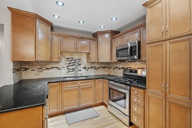 a kitchen with stainless steel appliances granite countertop a stove a sink and a refrigerator