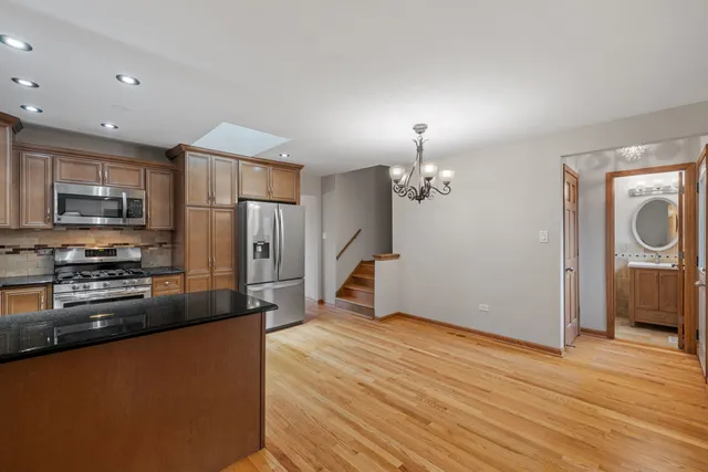 a kitchen with stainless steel appliances granite countertop a refrigerator a stove and a wooden floors