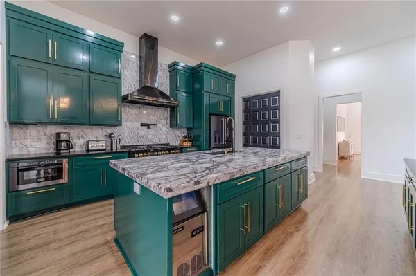 a kitchen with stainless steel appliances granite countertop a refrigerator a sink and white cabinets with wooden floor