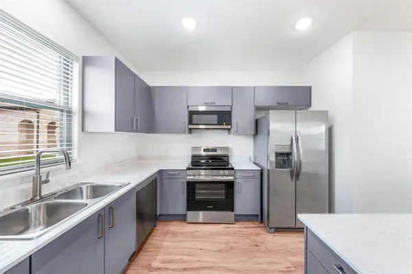 a kitchen with stainless steel appliances kitchen island granite countertop a stove a sink and a refrigerator