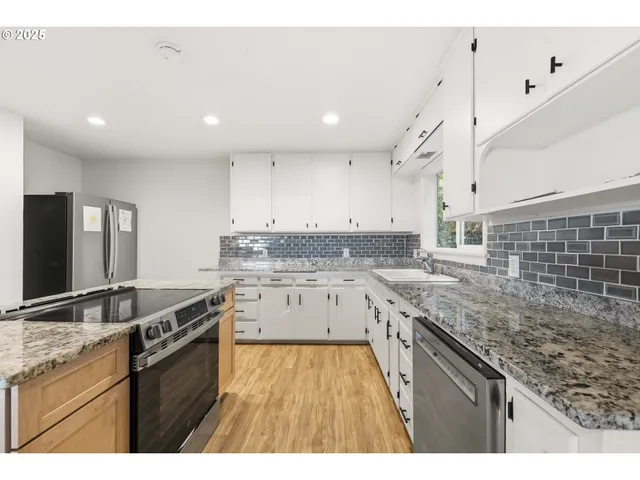 a view of a kitchen with kitchen island wooden floor and stainless steel appliances