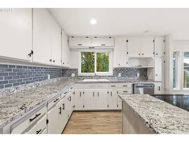 a kitchen with kitchen island granite countertop a stove sink and cabinets