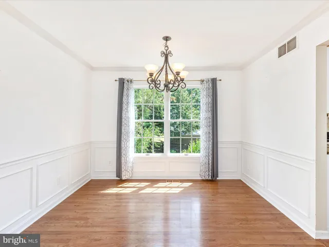a view of an empty room with wooden floor and windows