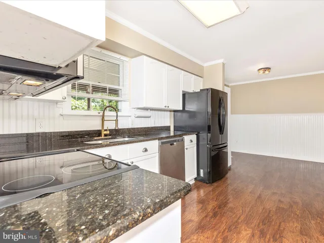 a kitchen with a refrigerator stainless steel appliances wooden floor and cabinets