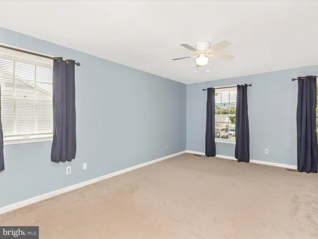a view of an empty room with window and chandelier fan
