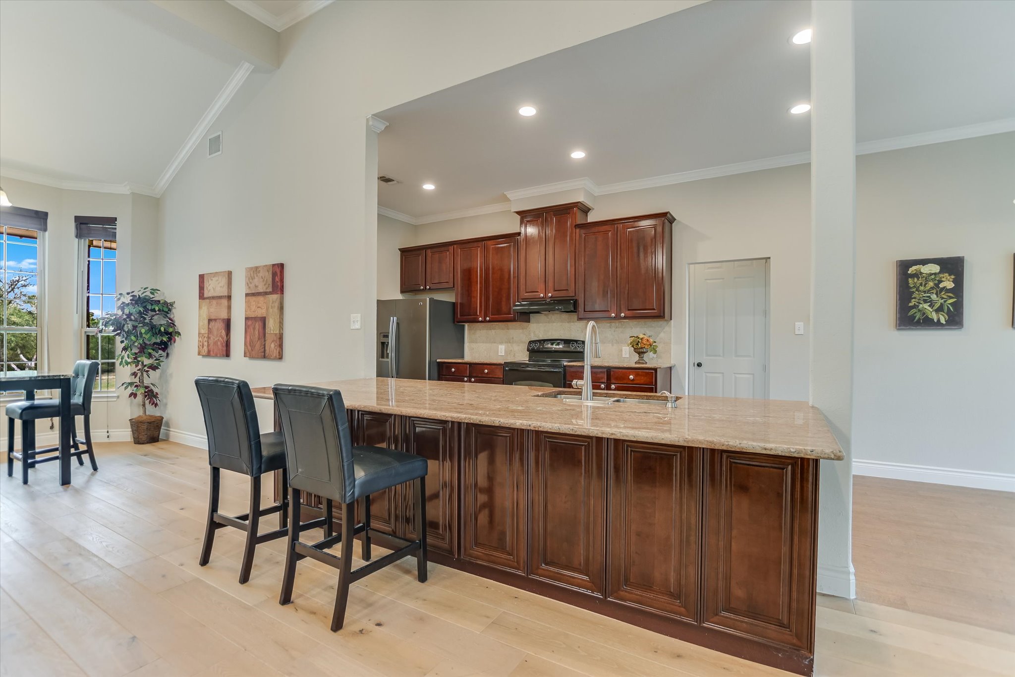300 Round Rock Road Wimberley, TX 78676 - Photo 7 of 23 Kitchen with stainless steel fridge, electric range, a kitchen breakfast bar, light stone countertops, and vaulted ceiling