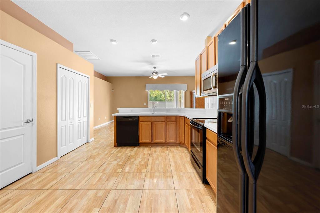 4211 Blakemore Place Spring Hill, FL 34609 - Photo 13 of 42 a large kitchen with stainless steel appliances kitchen island a large counter top and a refrigerator