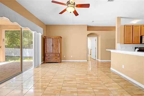 a view of an empty room with window and a kitchen