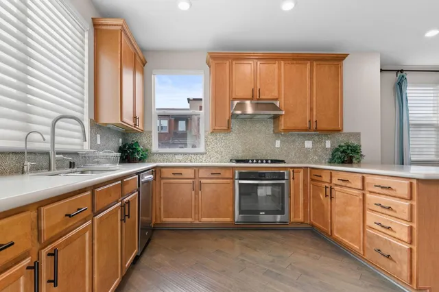 a kitchen with stainless steel appliances granite countertop a sink stove and cabinets