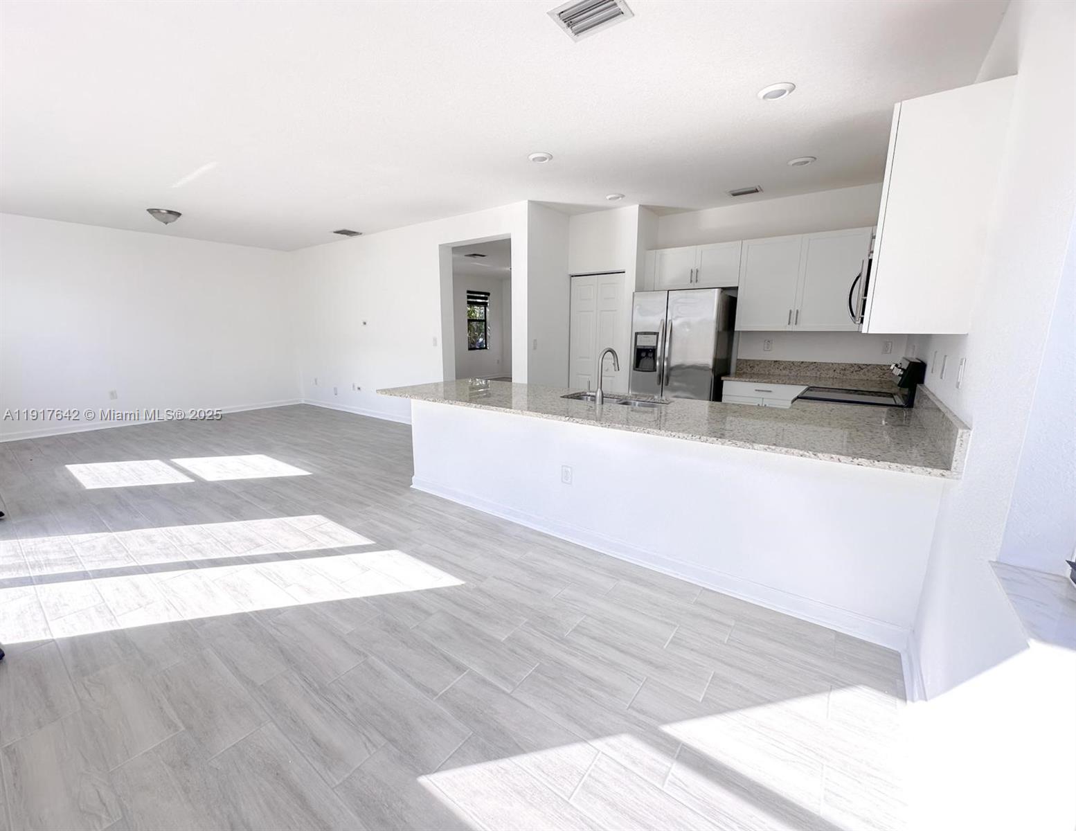 244 Northeast 210th Way, Unit 244 Miami, FL 33179 - Photo 15 of 32 a large white kitchen with a sink wooden floor and a granite counter top
